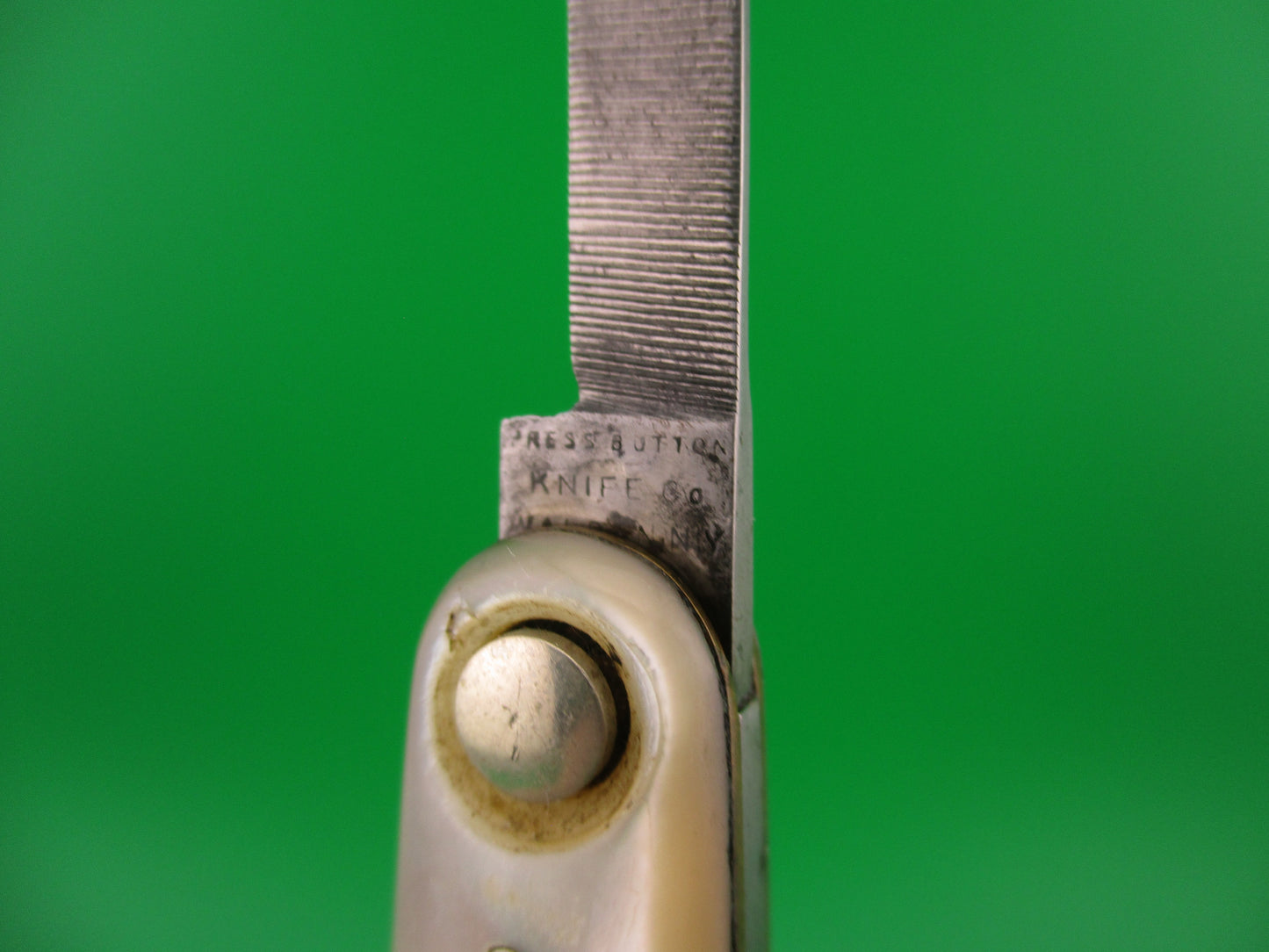 Close-up of a knife blade with a green background