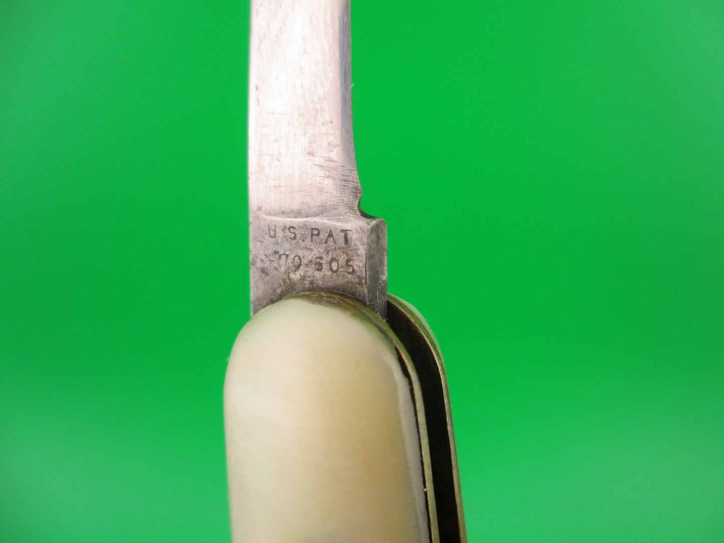 Close-up of a knife with 'U.S. PAT' engraving on a green background