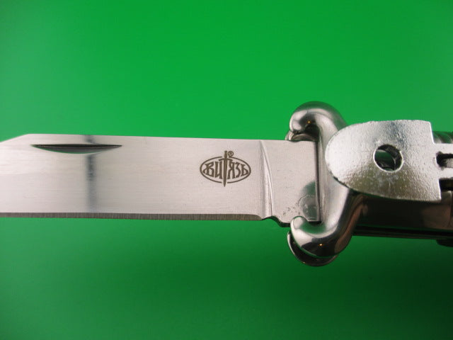 Close-up of a knife with a visible brand logo on a green background