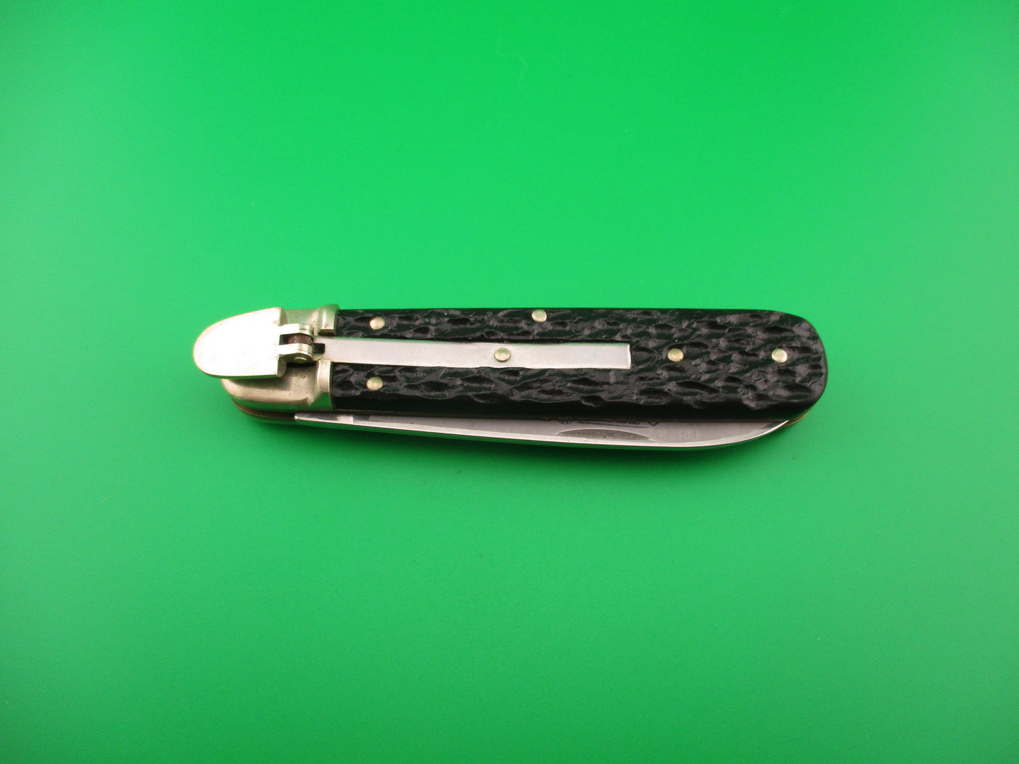 Pocket knife with a black handle on a green background