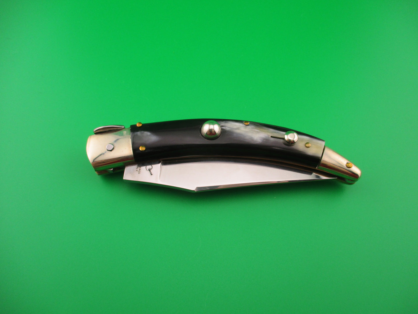 Folding knife with decorative handle on a green background