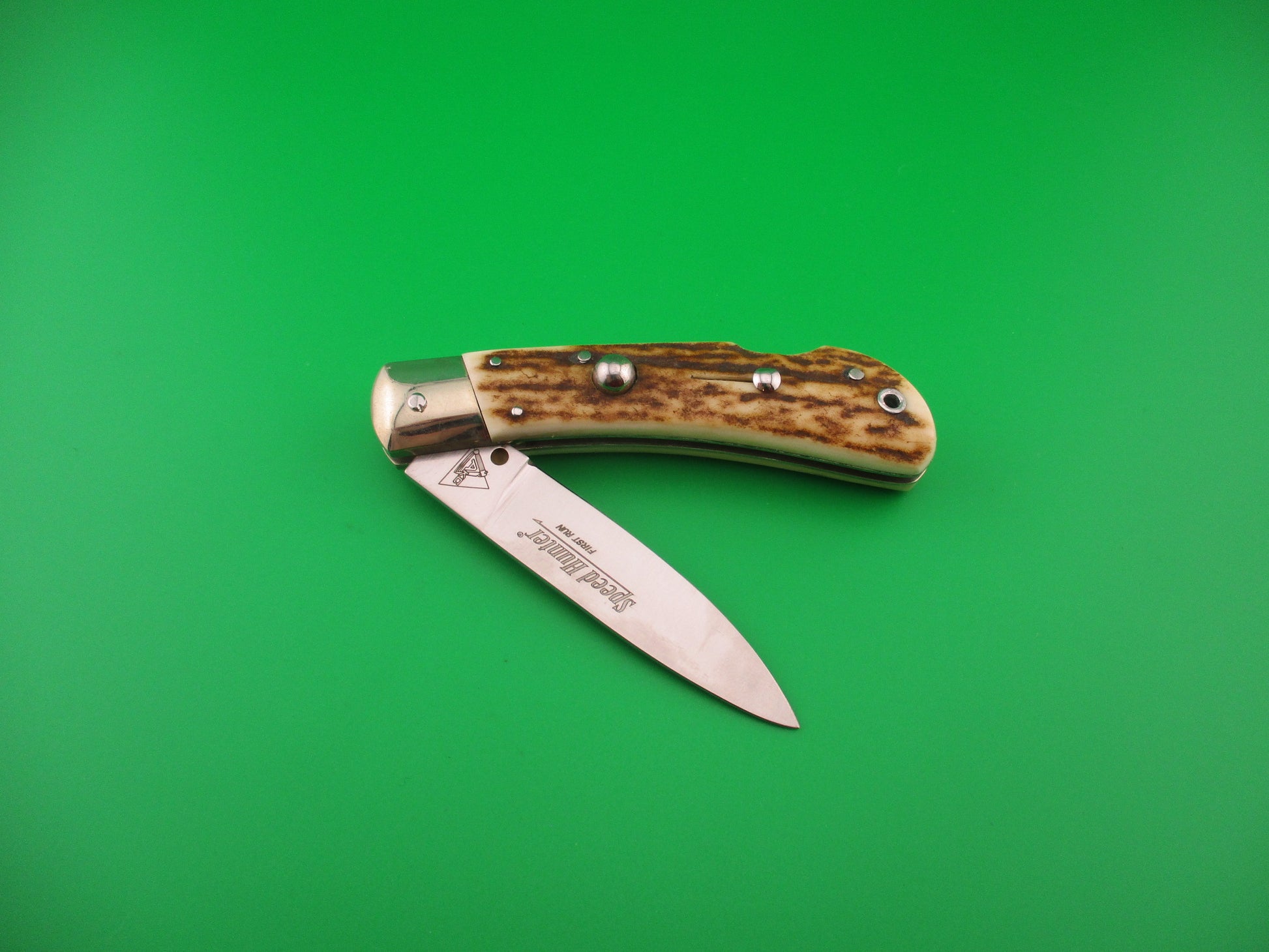 Folding knife with staghorn handle on a green background