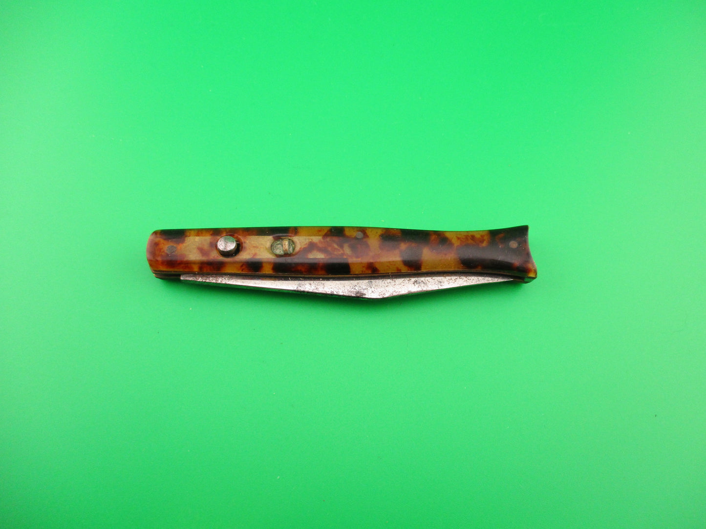 Folding knife with tortoiseshell handle on a green background
