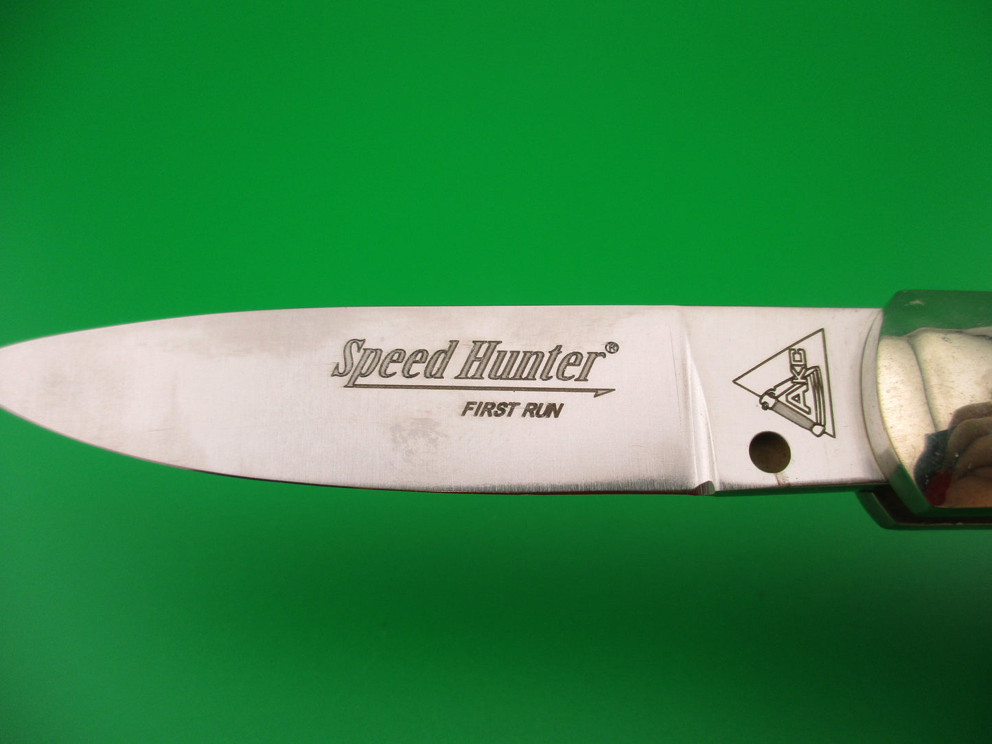 Knife blade with 'Speed Hunter' branding on a green background