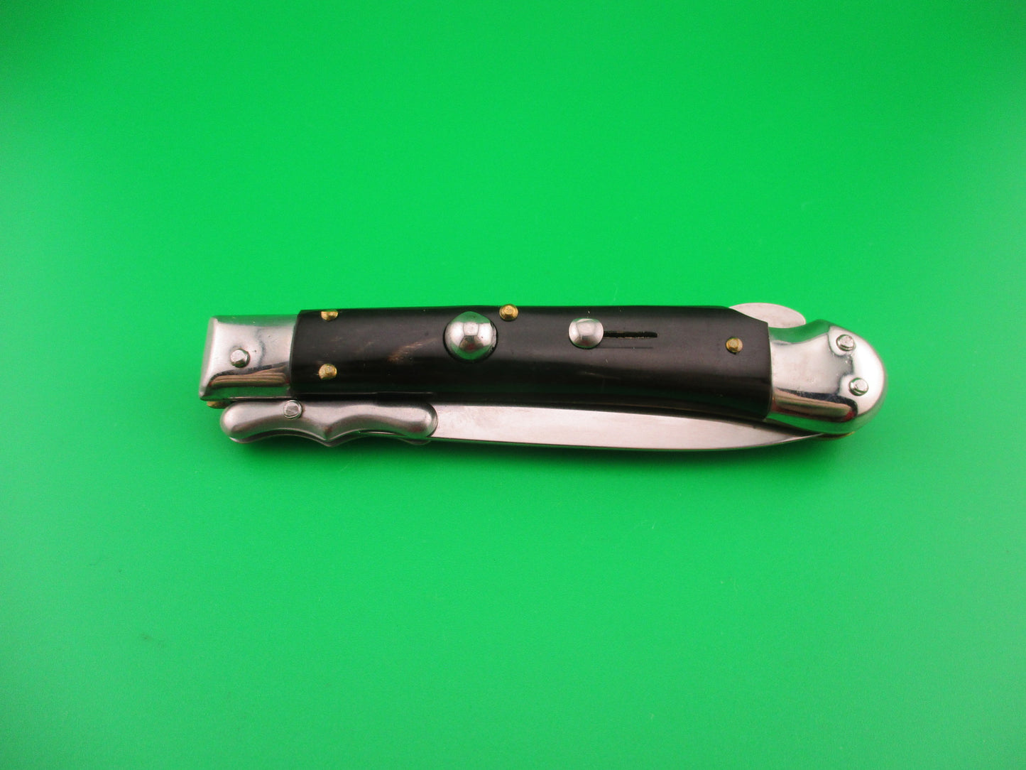 Pocket knife with black handles on a green background