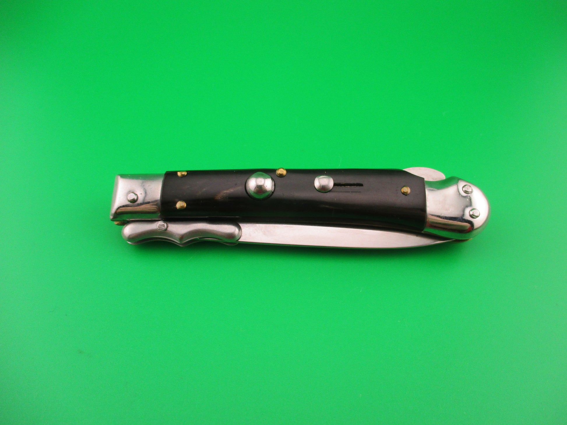 Pocket knife with black handles on a green background