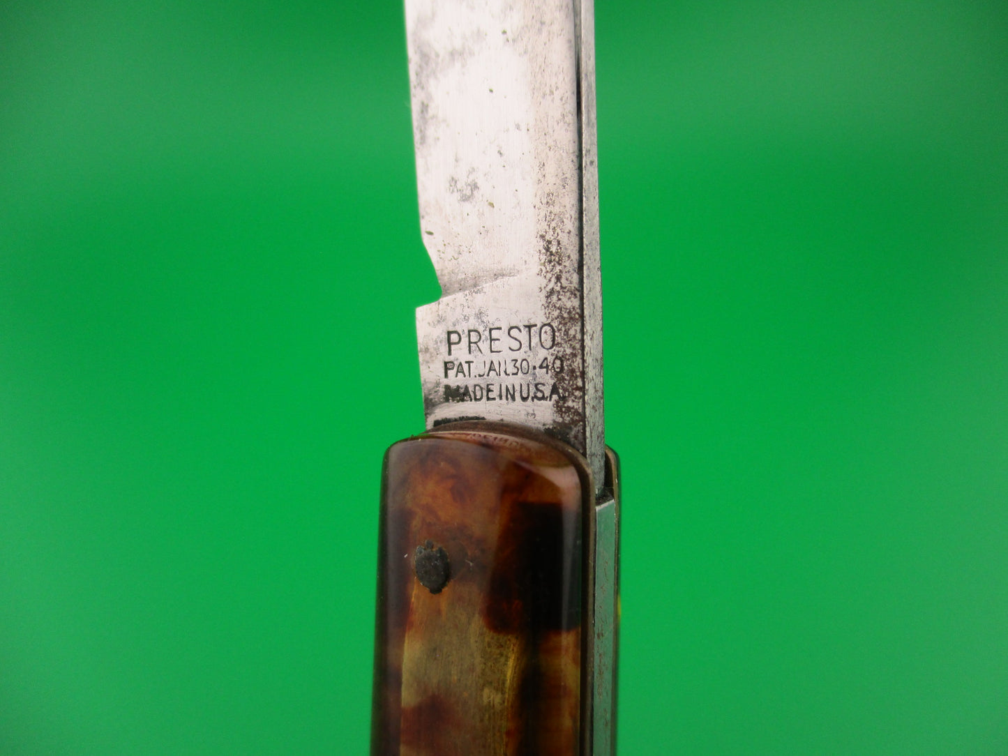 Close-up of a knife with 'Presto' branding on a green background