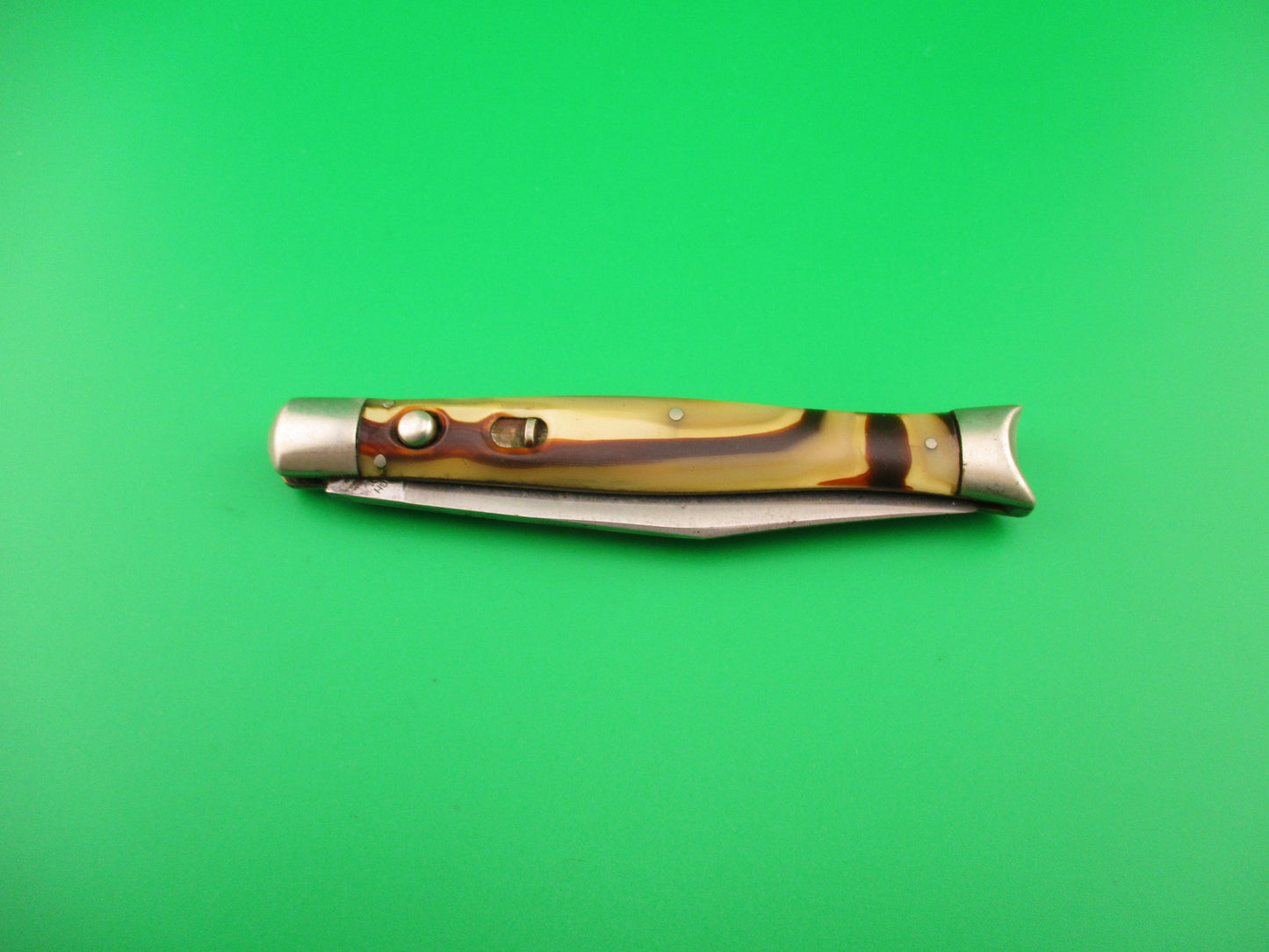 Folding knife with a decorative handle on a green background