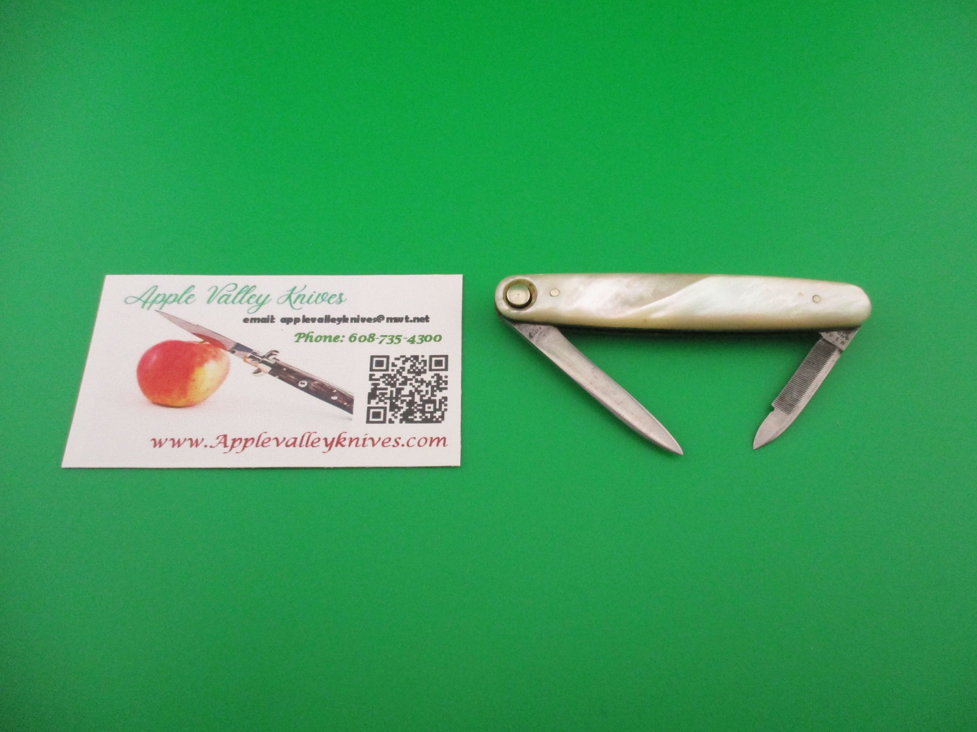 Small pocket knife and business card on a green background