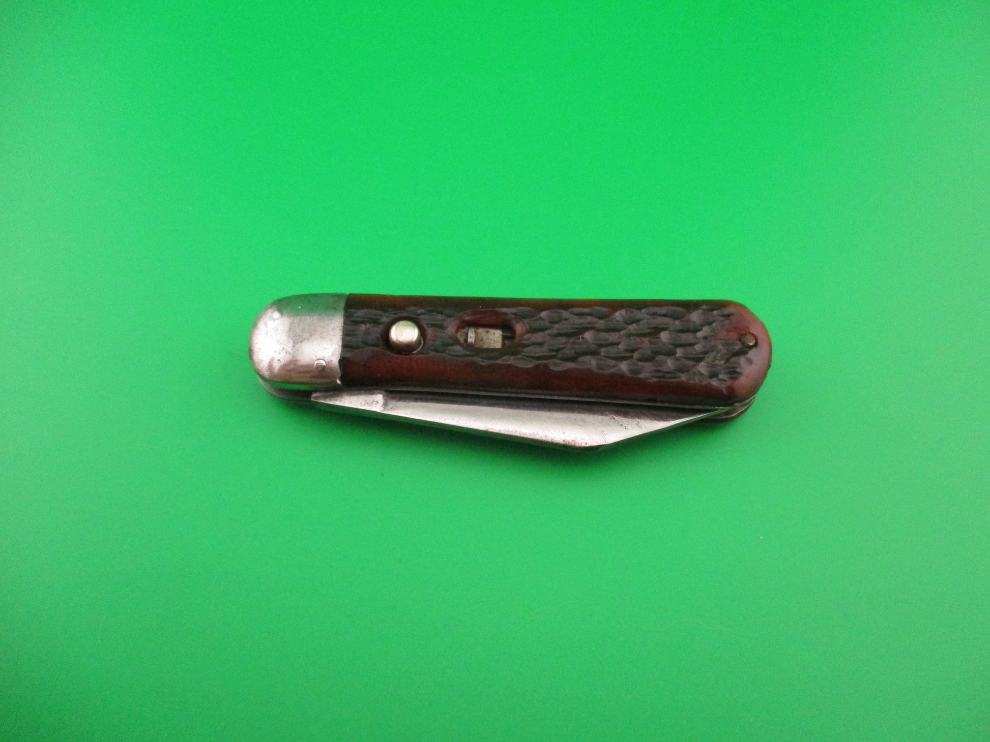 Pocket knife with brown handle on a green background