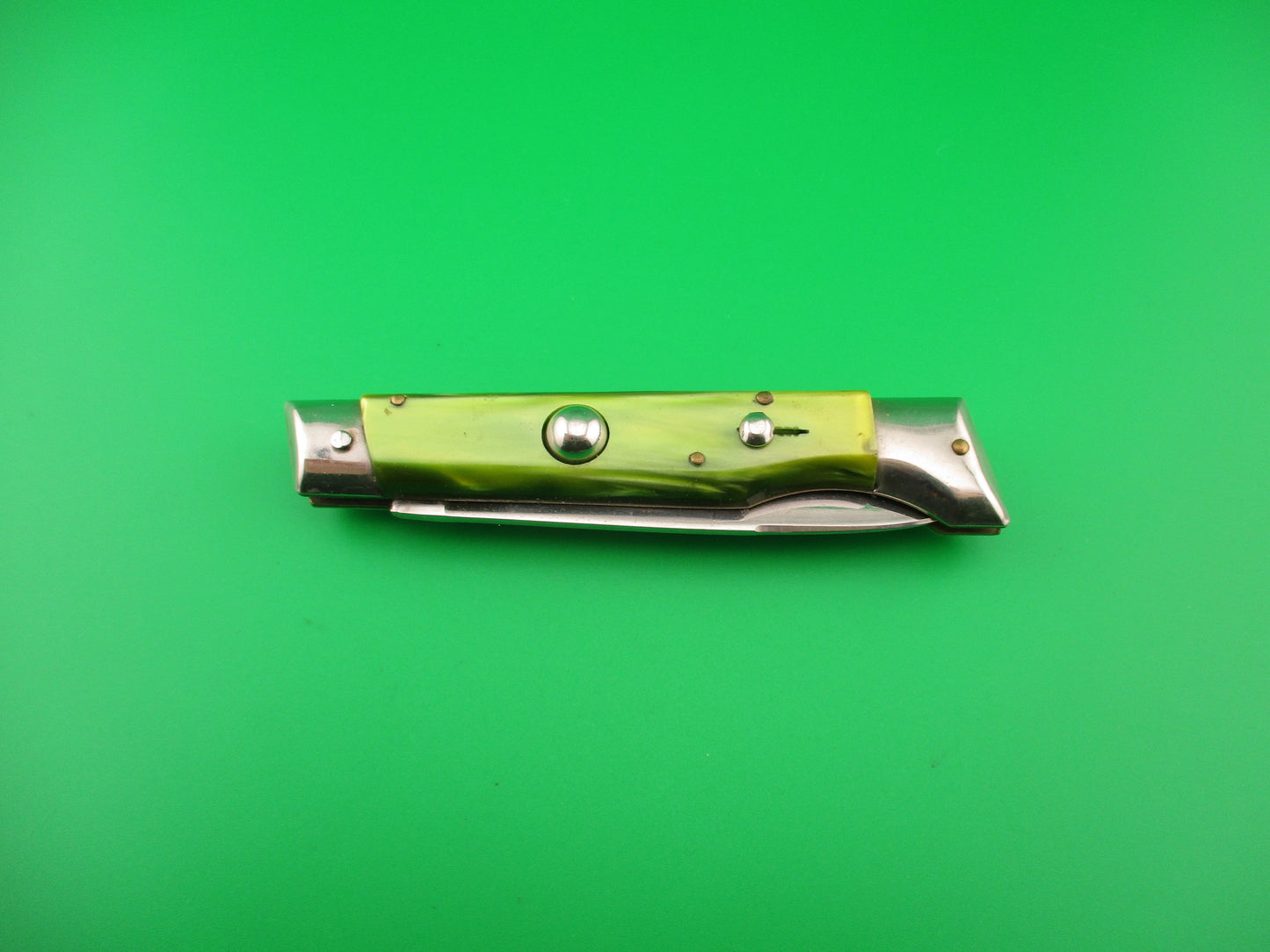 Folding knife with green handle and silver blade on a green background
