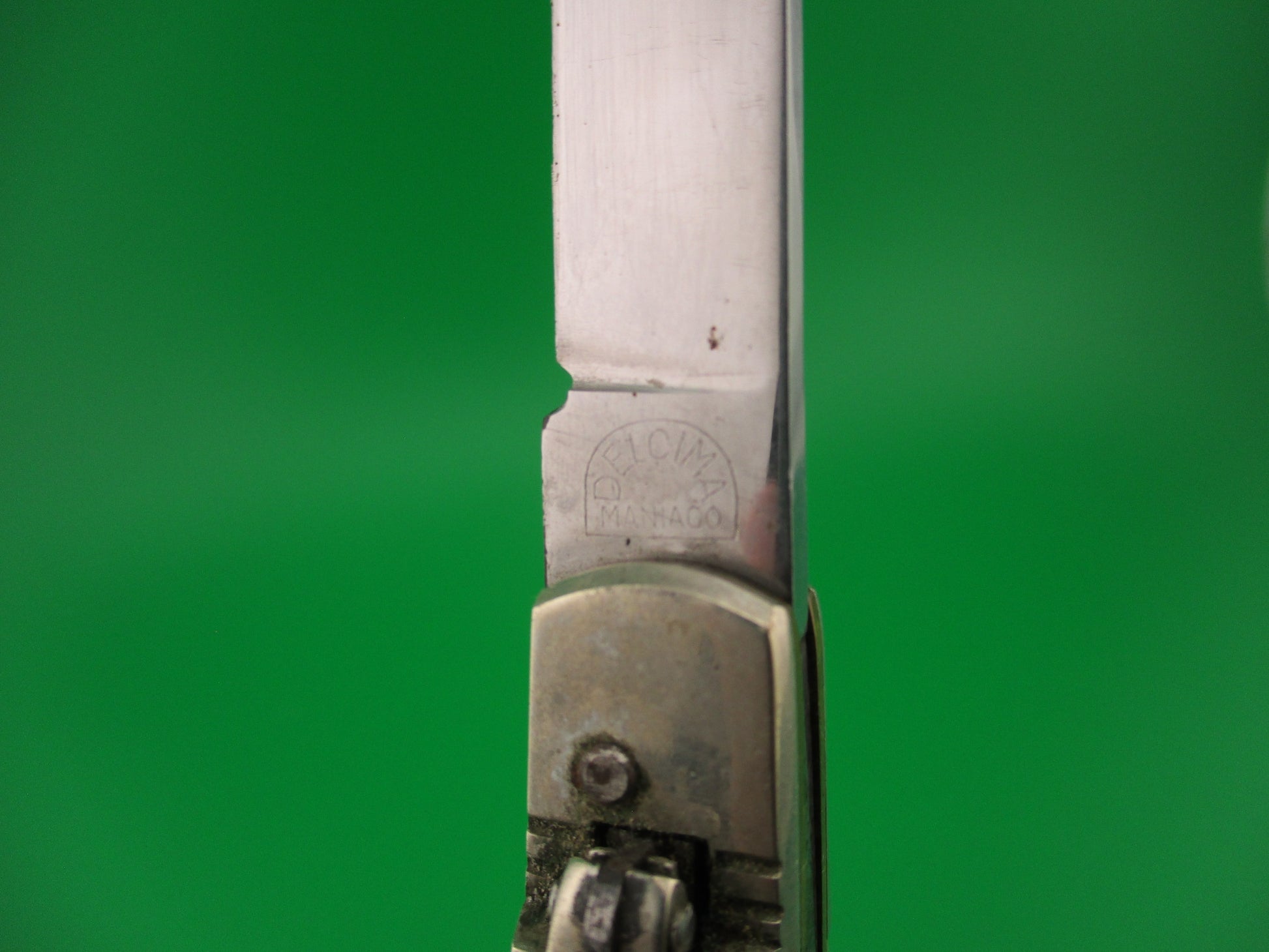Close-up of a knife blade with a brand logo on a green background