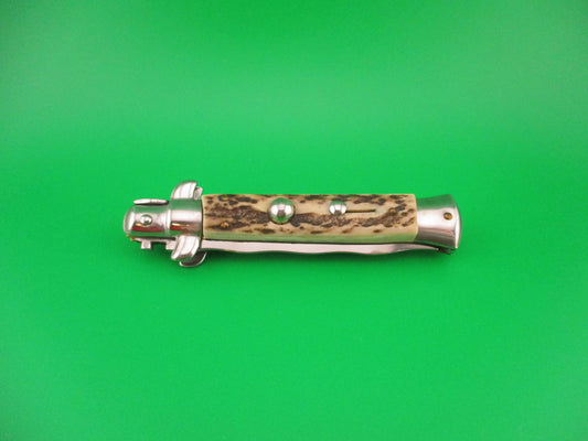 Metallic folding knife with a decorative handle on a green background