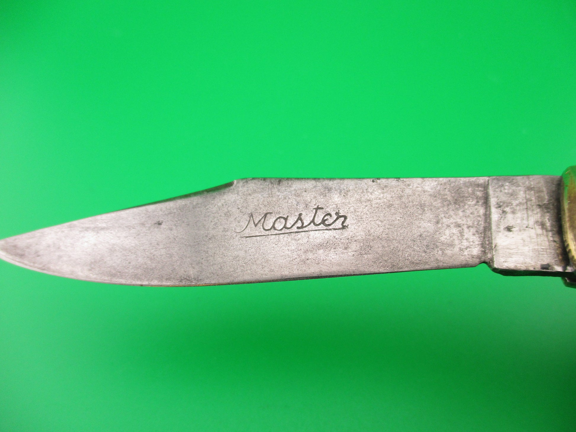 Knife blade with 'Master' engraving on a green background