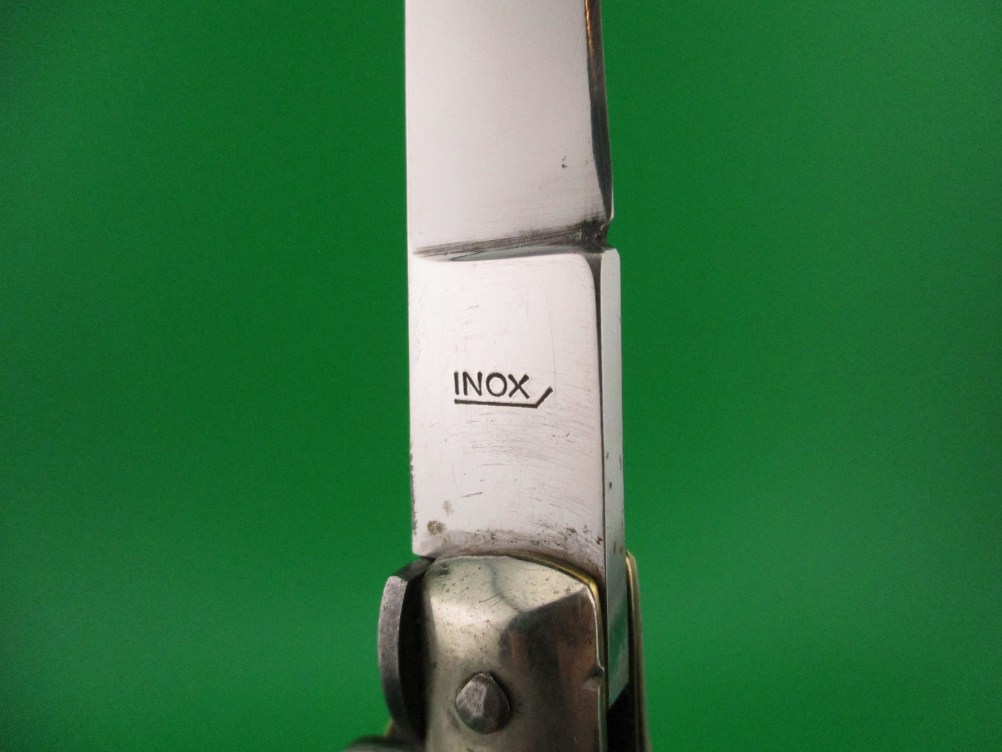 Close-up of a metallic object with 'INOX' branding on a green background