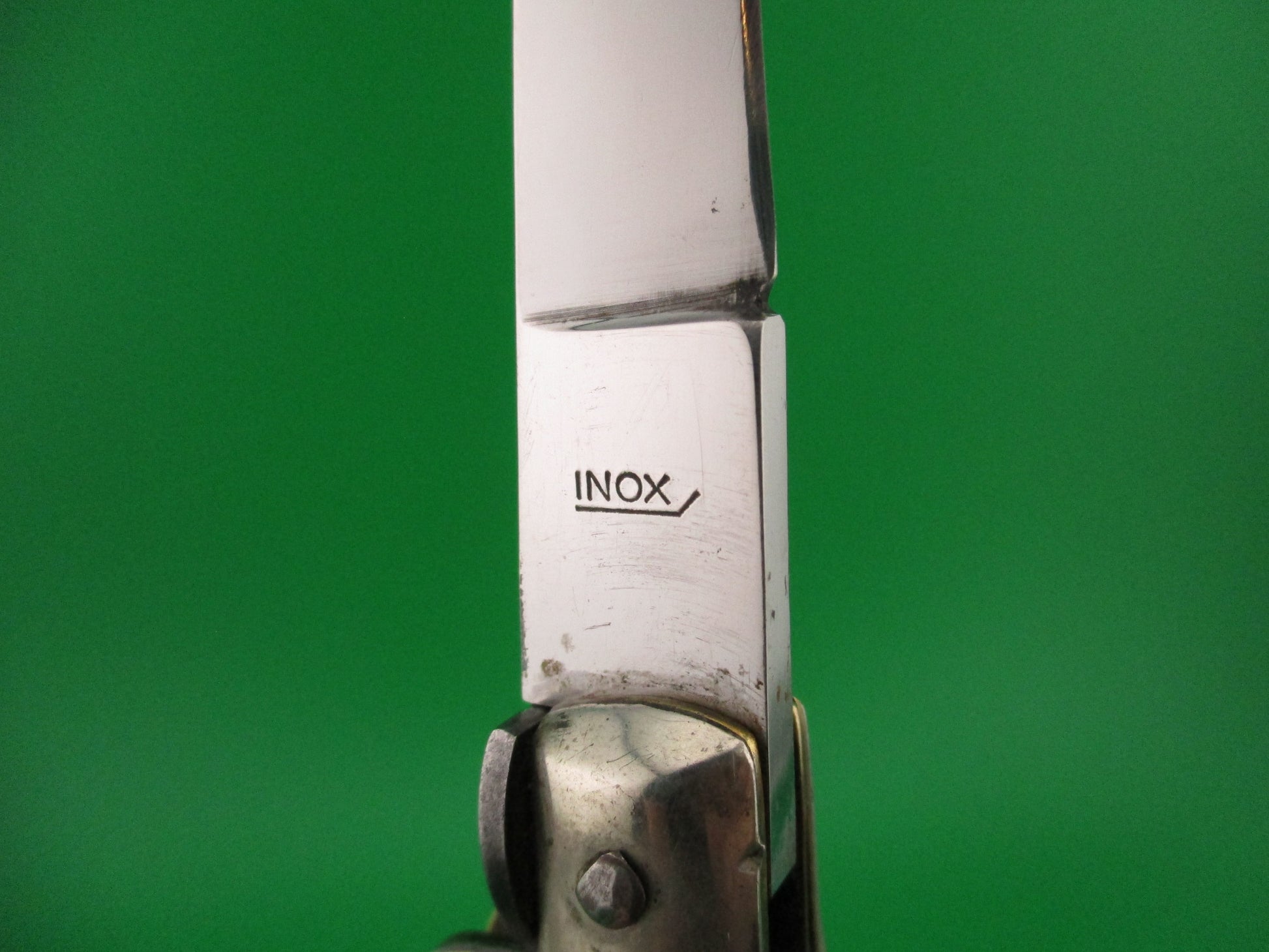 Close-up of a metallic object with 'INOX' branding on a green background