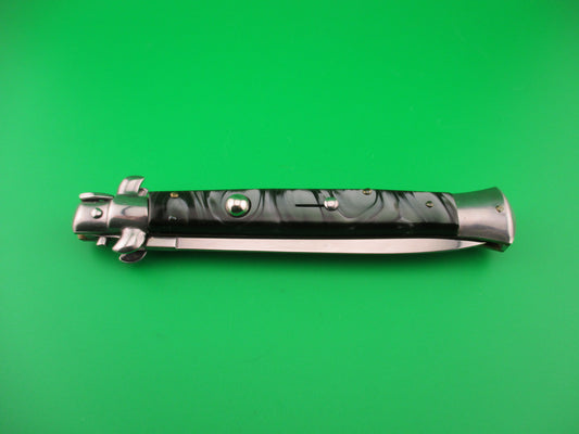 Folding knife with a metallic handle on a green background