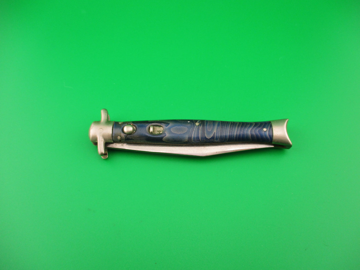 Decorative knife with a blue handle on a green background