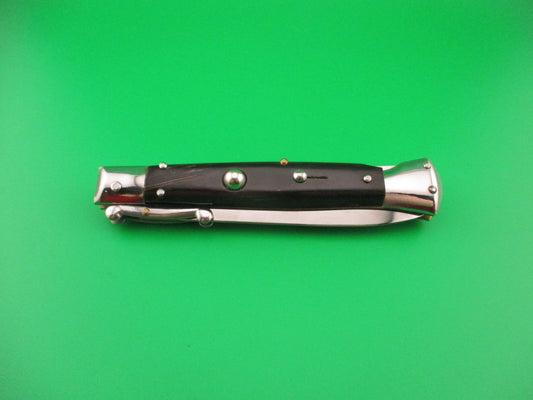 Folding knife with black handle and silver blade on a green background