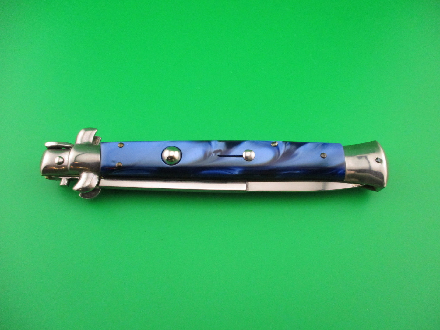 Folding knife with blue handle and silver blade on a green background