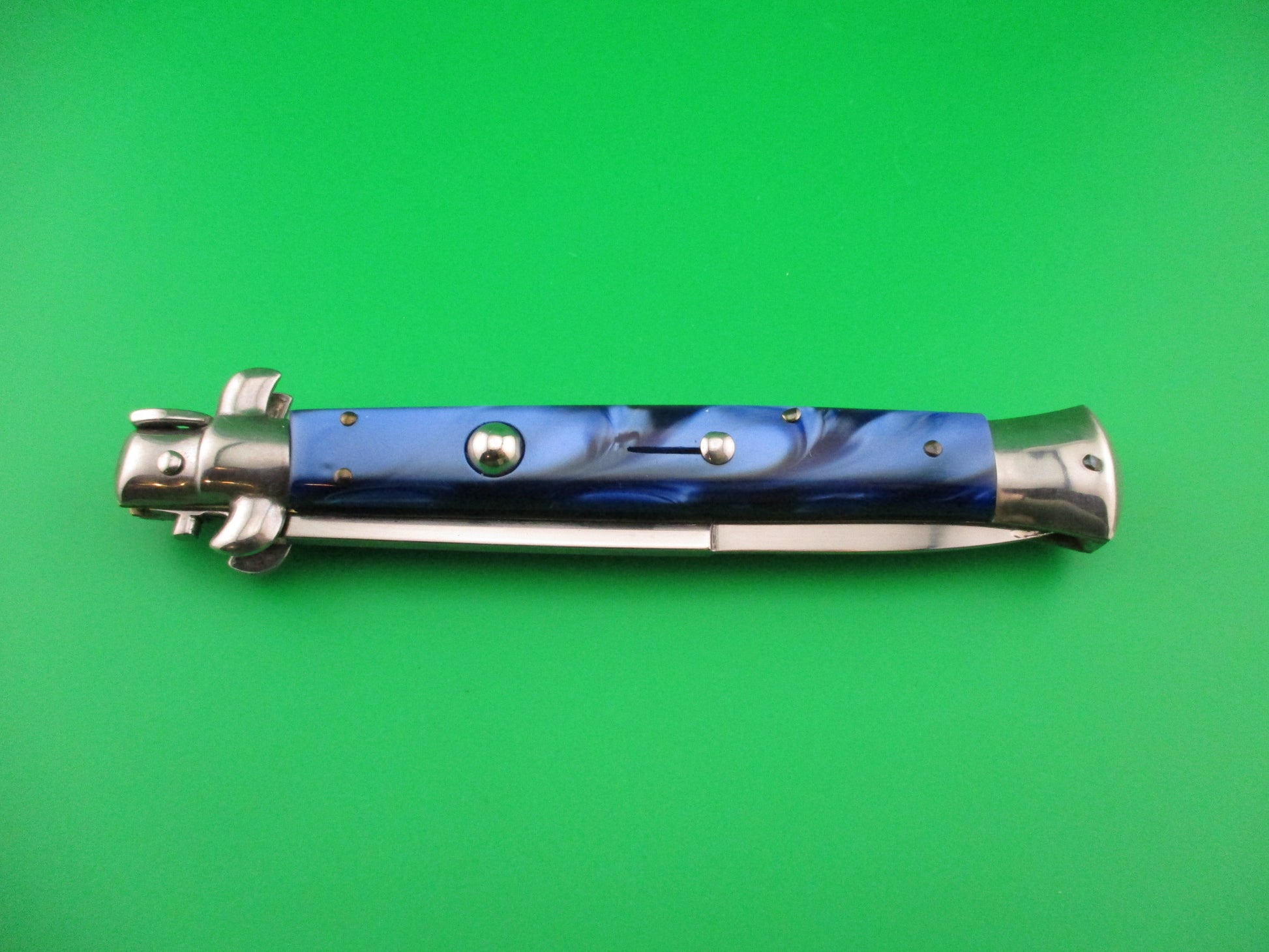 Folding knife with blue handle and silver blade on a green background