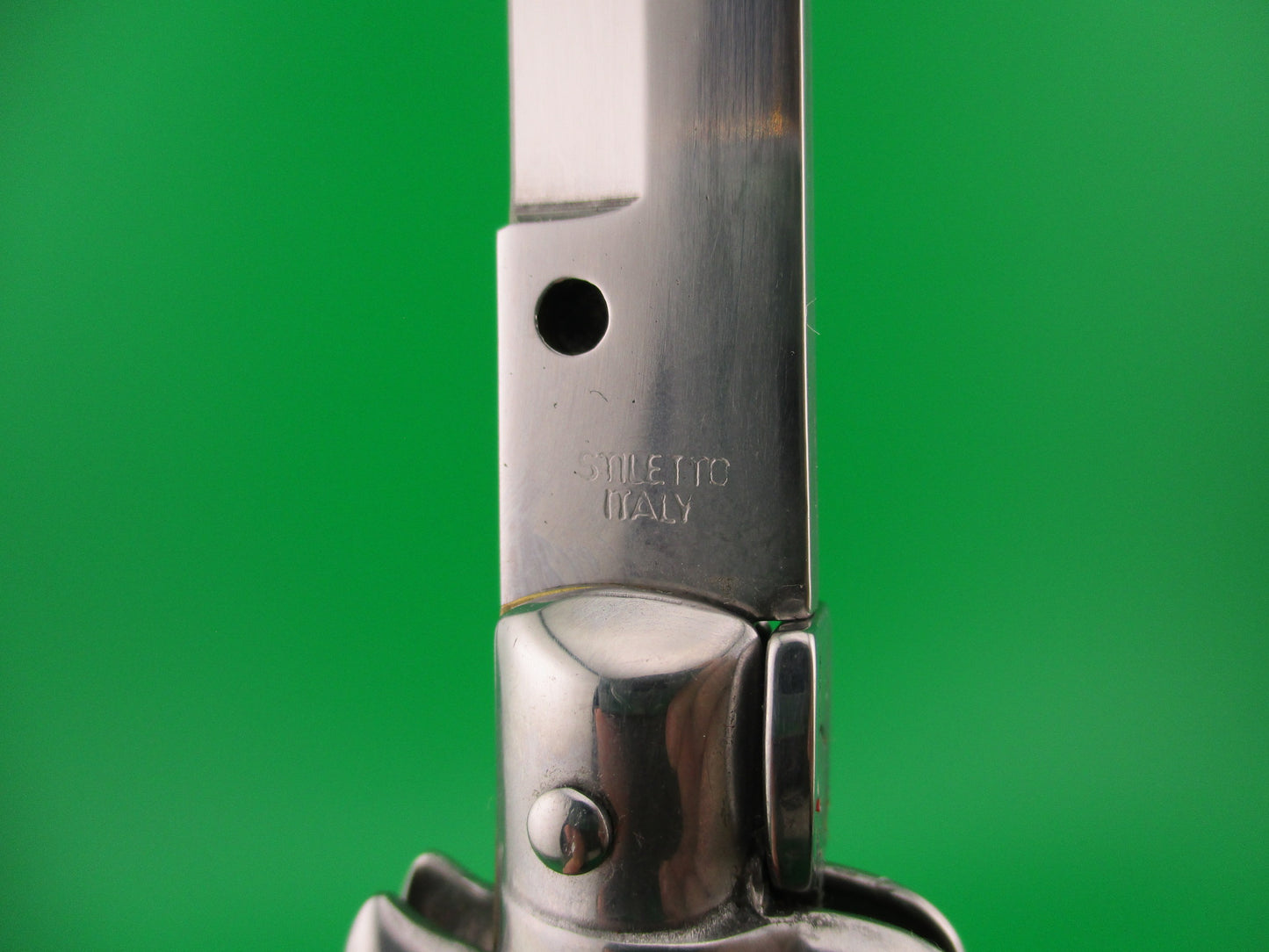 Close up of knife blade with 'Stiletto Italy' engraving on a green background