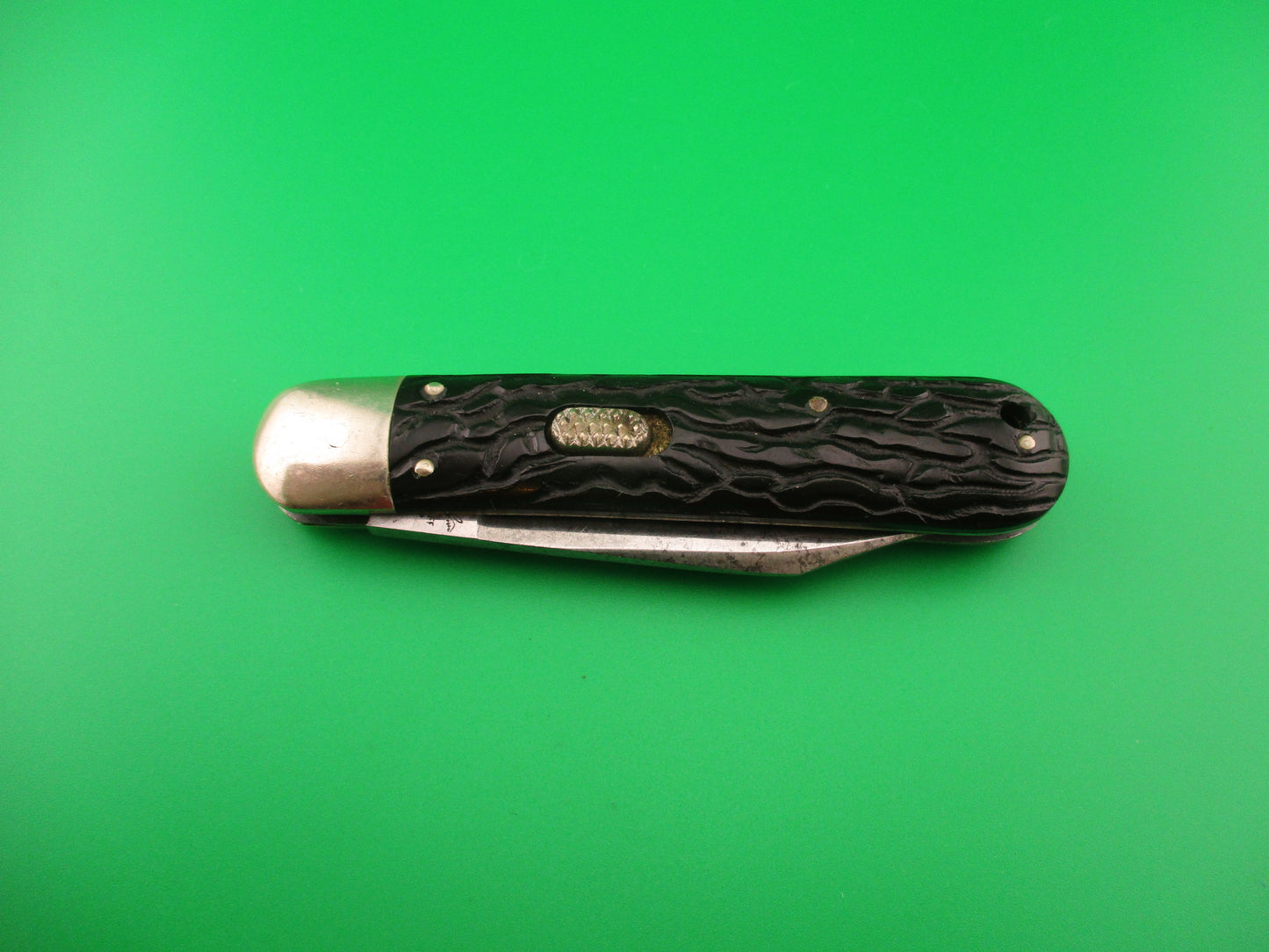 Pocket knife with black handle and silver blade on a green background