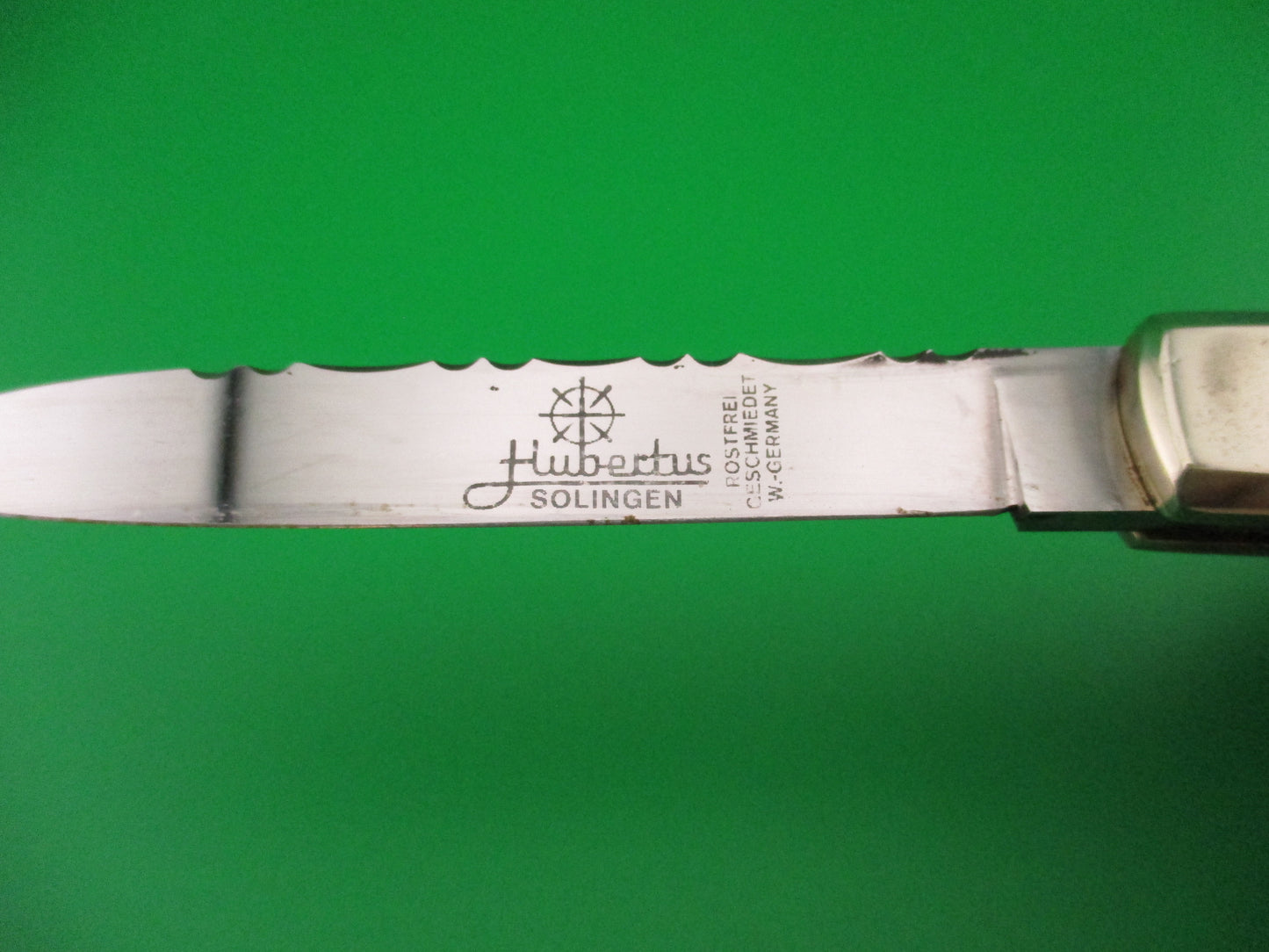Knife blade with 'Hubertus Solingen' engraving on a green background
