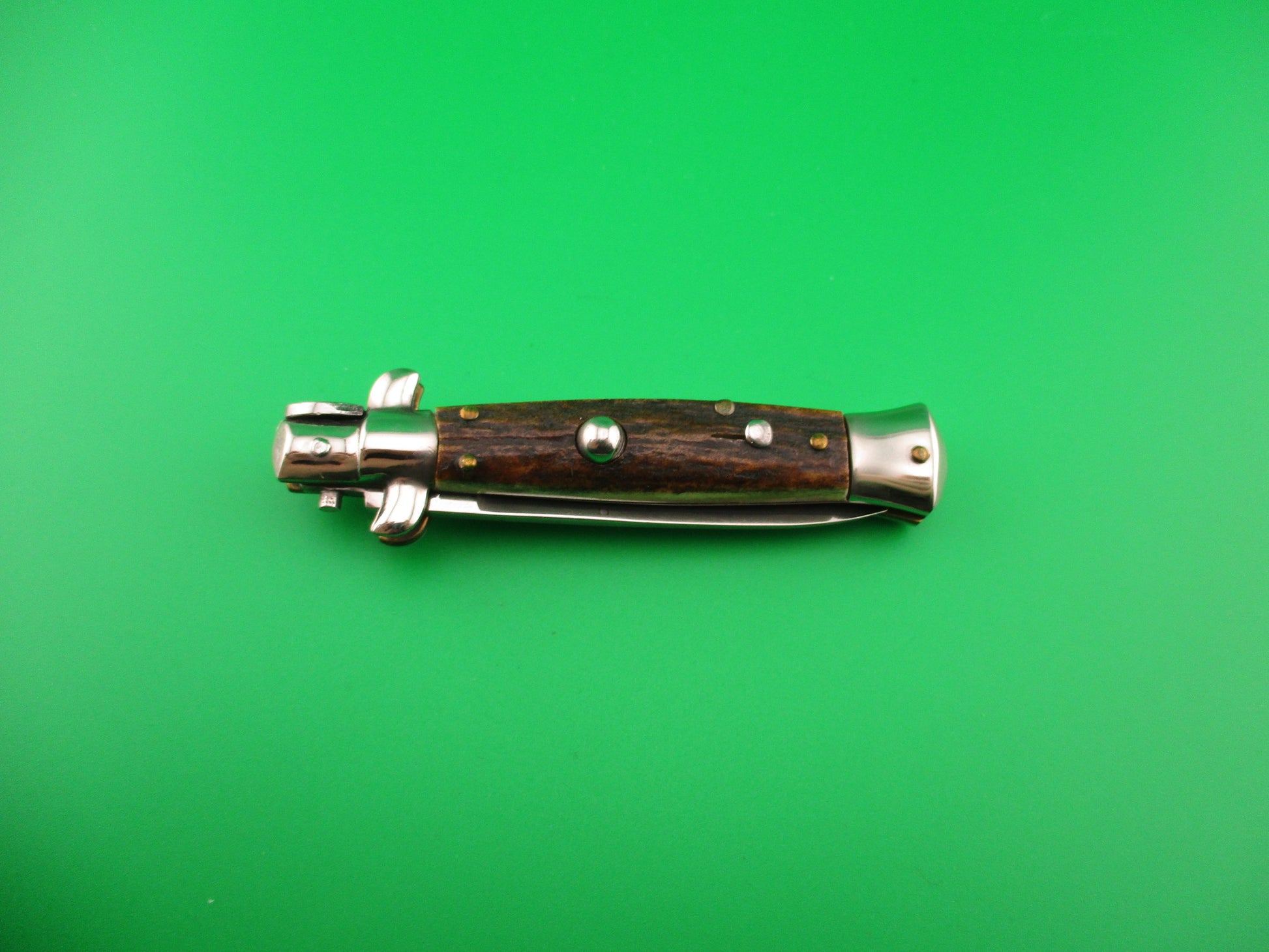 Wooden-handled tool on a green background