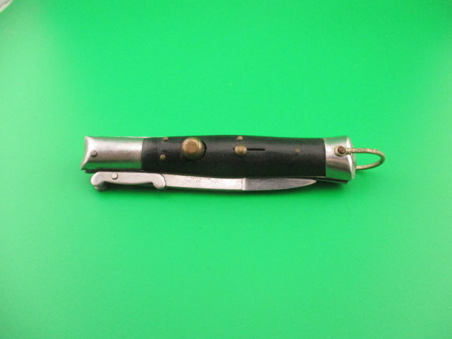 Folding knife with black handle and silver blade on a green background