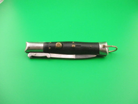 Folding knife with black handle and silver blade on a green background
