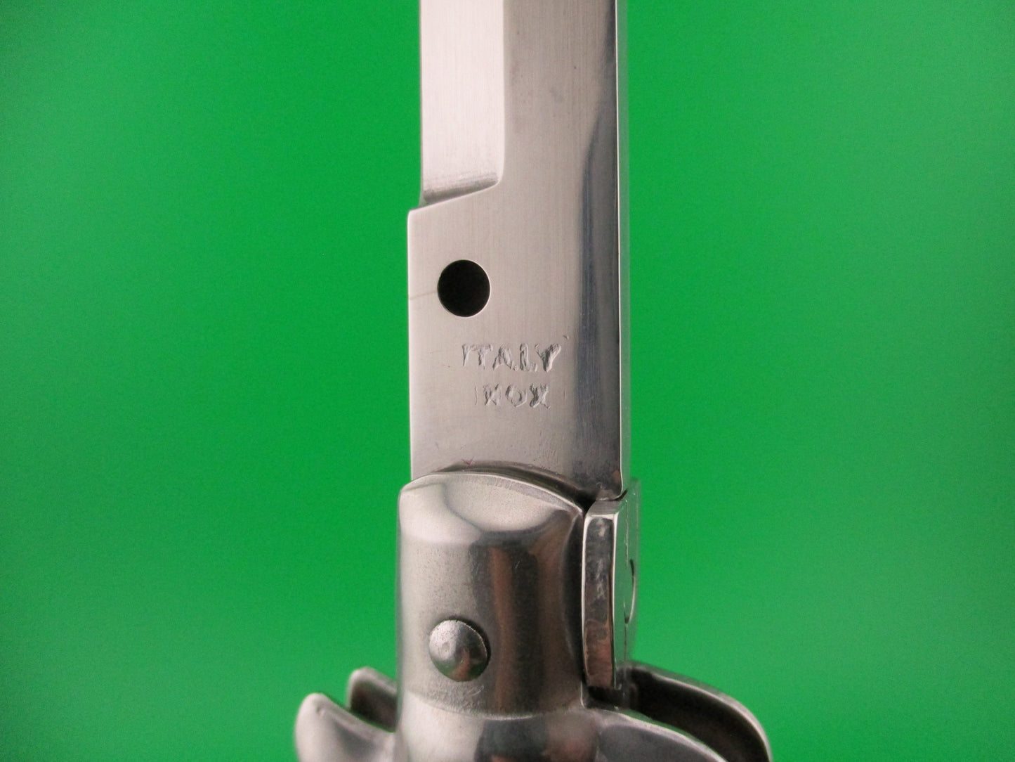 Metal folding knife with 'Italy Inox' branding on a green background