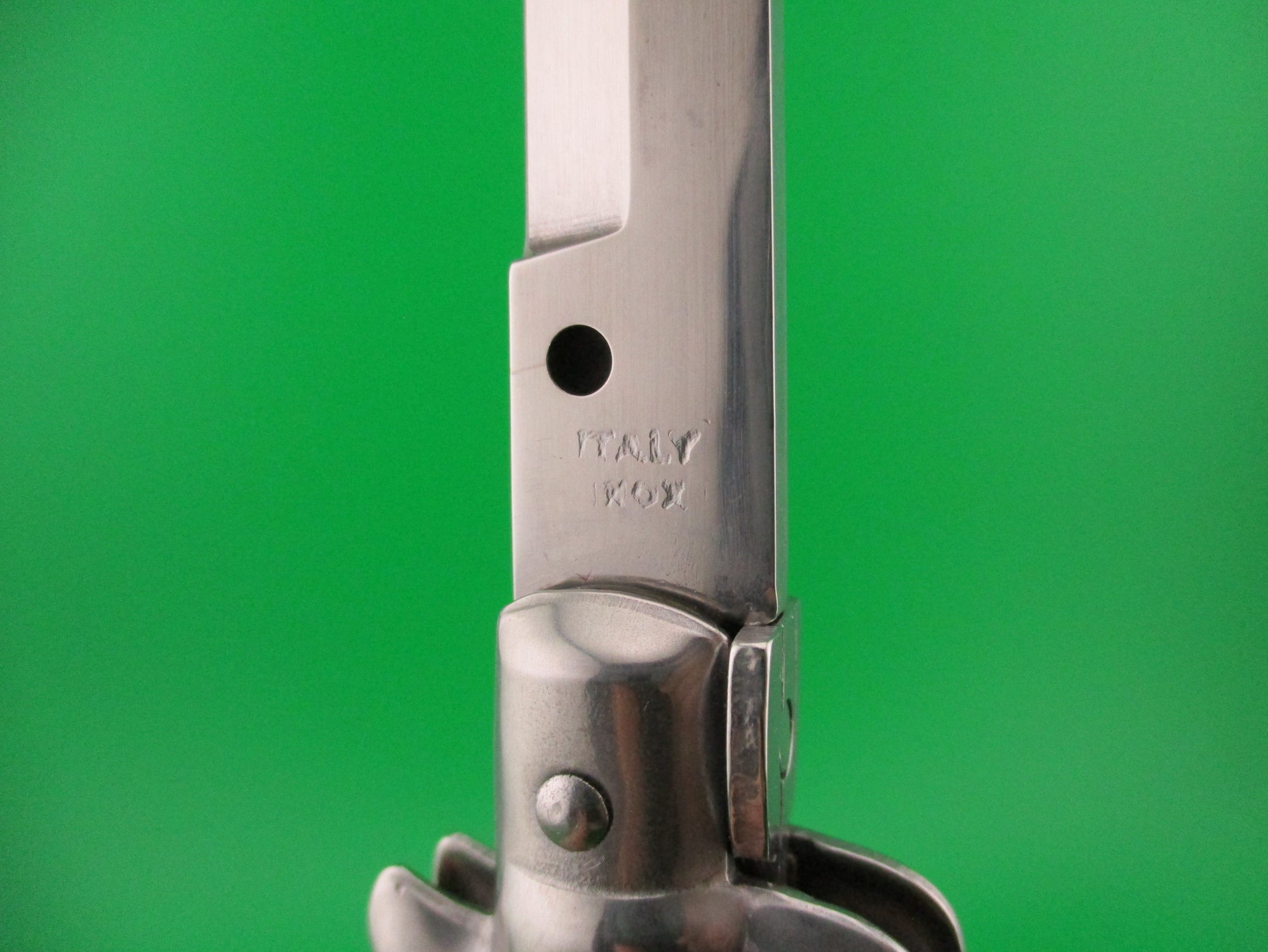 Metal folding knife with 'Italy Inox' branding on a green background