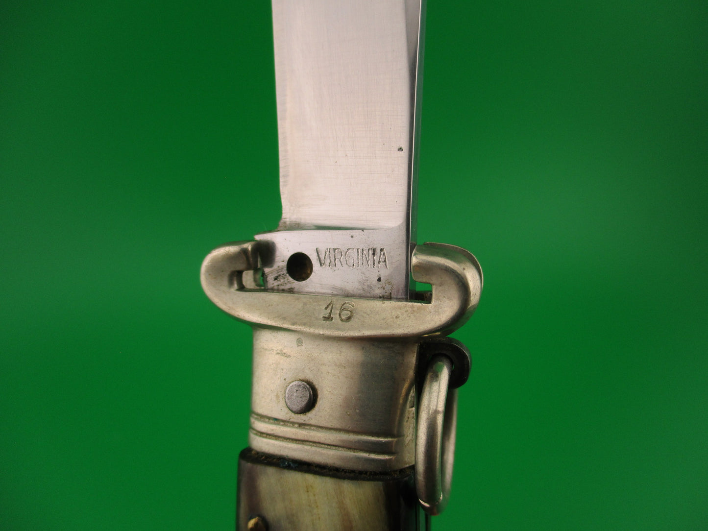 Close-up of a knife blade with 'Virginia' engraving on a green background