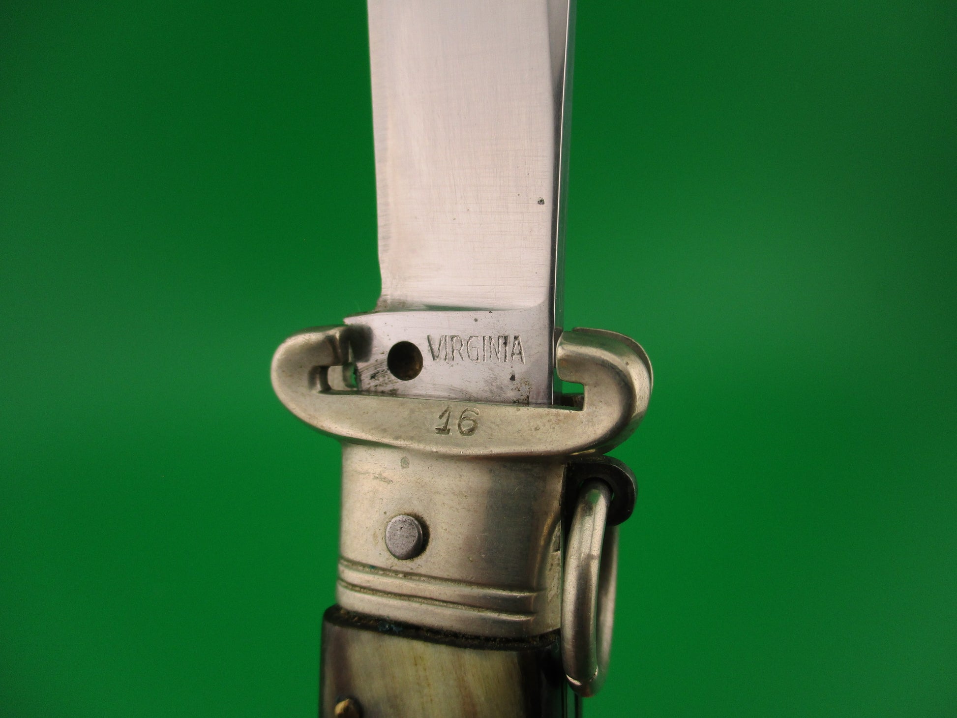 Close-up of a knife blade with 'Virginia' engraving on a green background